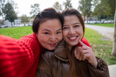 Photo for Two gorgeous smiling chinese female friends take a selfie at a public park. - Royalty Free Image