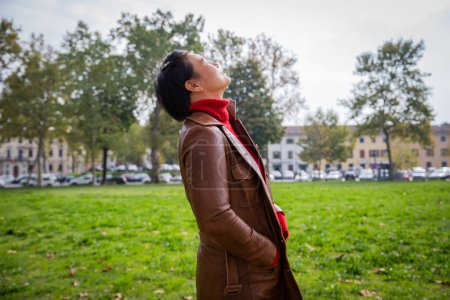 Foto de Una mujer asiática con la cara hacia arriba respira aire fresco durante un día otoñal en un parque público - Imagen libre de derechos
