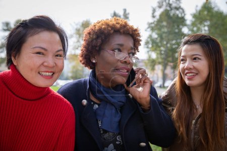 Photo for Three mature women together in a park, friendship between people of different ethnicities - Royalty Free Image