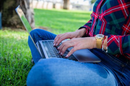 Foto de Close-up of a girl's hands typing on her laptop sitting in a public park - Imagen libre de derechos