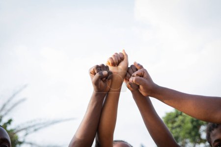 Photo for Four fists of African people united in sky, photo with copy space above - Royalty Free Image