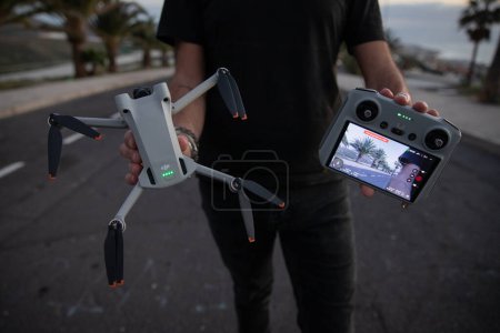 Téléchargez les photos : Tenerife, Spain, 27th January 2023: A drone pilot holding the new DJI mini 3 Pro drone and its remote controller with screen - en image libre de droit