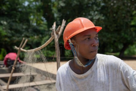Téléchargez les photos : Portrait of a young African fisherman wearing protective helmet and looking around - en image libre de droit