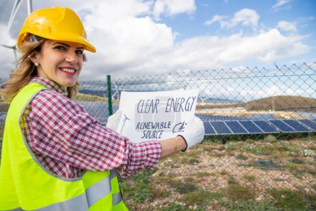 Photo for A female engineer at a solar power plant with a sheet that says "clean energy renewable source" - Royalty Free Image