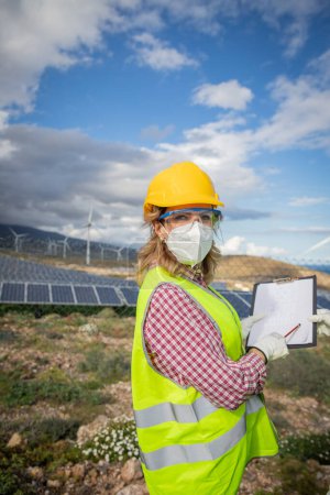Photo for A female engineer at a solar power plant during work, she wears protective workwear. - Royalty Free Image