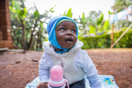 Téléchargez les photos : Bébé garçon africain mignon et magnifique regardant le ciel avec sourire. - en image libre de droit