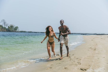 An interracial couple has fun on the beach during vacation.