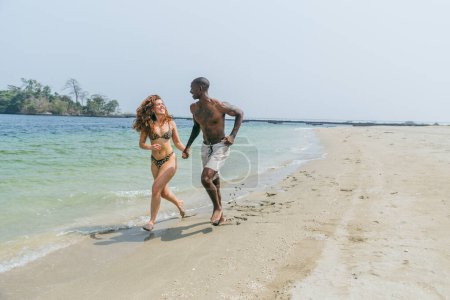 Un couple court sur la plage et s'amuse pendant leurs vacances balnéaires en Afrique.