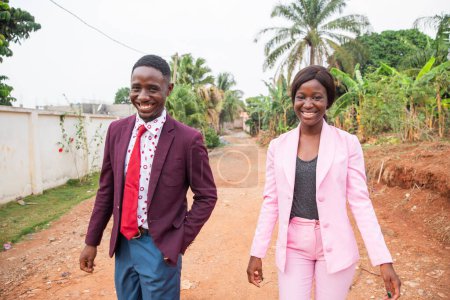 Two colleagues walking on their way to work, African business man and woman together smiling.