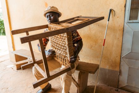 A blind man is crafting a chair, reintegration into the society of people with disabilities