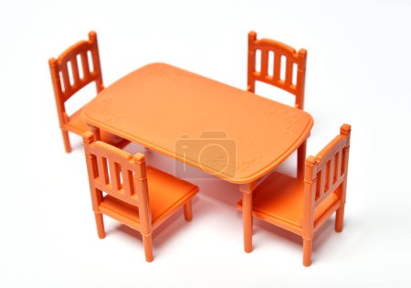 Plastic toy furniture table with chairs on white background, selective foreground focus. Model of miniature doll house furniture.