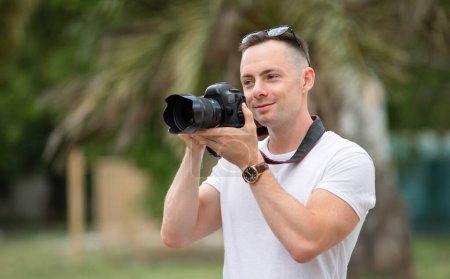 Foto de Hombre fotógrafo tomar una foto en el parque de verano con palmera en el fondo - Imagen libre de derechos