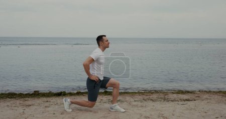 Photo for Lunges Exercise - Fitness Man Doing Lunge Workout Exercise at the beach - Royalty Free Image