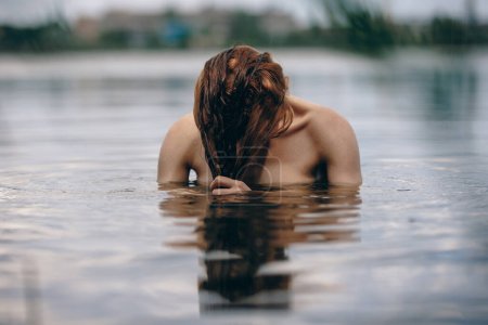 Portrait of naked woman swimming in the lake or river hiding behind hair Stickers 665029260