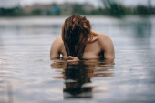 Portrait of naked woman swimming in the lake or river hiding behind hair Stickers #665029260