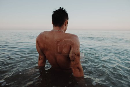 Vista trasera de un hombre sentado en el mar
