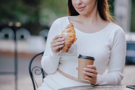 Photo for Croissant and coffee cup in a female hands sitting at outdoor cafe - Royalty Free Image