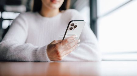 Téléchargez les photos : Plan recadré de femme méconnaissable en vêtements blancs à l'aide d'un smartphone assis dans un café - en image libre de droit