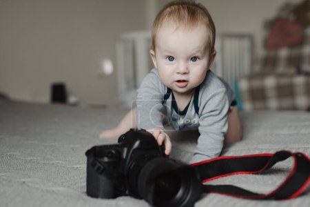 Téléchargez les photos : Petit garçon photographe couché avec caméra à la maison - en image libre de droit