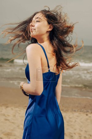 Photo for Happy woman in blue dress toss her hair at the beach - Royalty Free Image