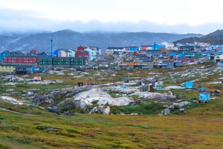 Téléchargez les photos : Où les chiens de traîneau vivent en été quand ils ne travaillent pas à Illulisat, Groenland. Derrière eux, il y a quelques-unes des maisons d'Illulisat peintes avec brio. - en image libre de droit