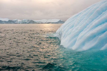 Téléchargez les photos : Bel iceberg strié révèle des lignes de turquoise entourées d'eaux vertes. Icefjord, Illulisat, Groenland. - en image libre de droit