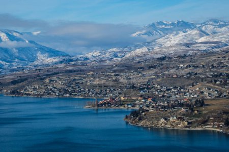 Beautiful winter view of Lake Chelan with blue lake and mountain tops covered in snow.