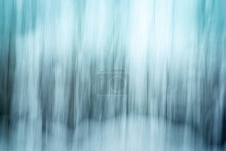 Abstract Intentional Camera Movement (ICM) a créé des lignes verticales douces de turquoise, d'émeraude et de blanc à partir de forêts enneigées.