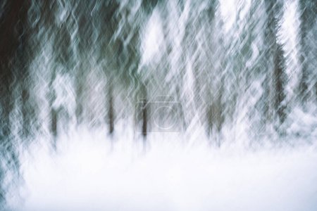 Wellenförmige Kamerafahrten während der Belichtung schaffen ein Abstrakt von Nadelbäumen in einer verschneiten Landschaft... perfekt für einzigartige Weihnachts- oder Wintergrüße!
