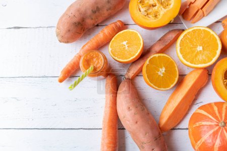 Orange colored  vegetables and fruits on white background. Flat lay with space for text