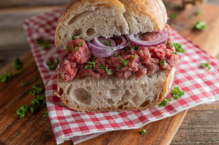 Sandwich de tártaro con cebolla roja y perejil en una baguette francesa. Primer plano y vista frontal