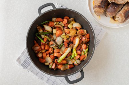 Mirepoix cocido o verduras de raíz para hacer salsa marrón o salsa. en una sartén para asar. Cocinar, hacer, preparar roulades de ternera, Parte de la serie