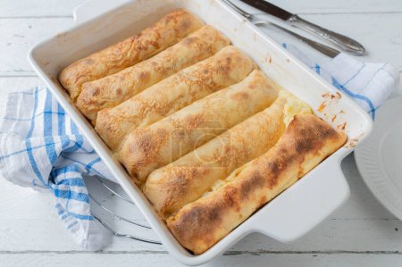 Dessert with pancakes. Filled with lemon, quark, egg yolk and sugar filling. Oven baked and served hot and ready to eat in a casserole dish