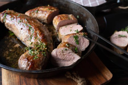Pork fillet with herb butter in a cast iron pan