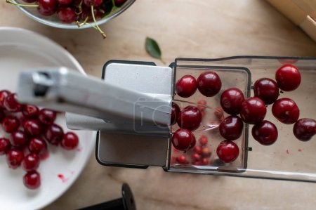 Photo for Sour cherries being processed in a cherry pitter on a marble countertop - Royalty Free Image
