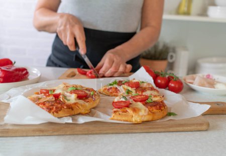 Photo for Pimped up baked frozen pizza is prepared by a woman in the kitchen - Royalty Free Image