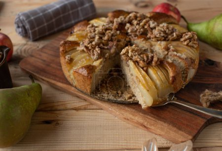 Juicy cake with pears and walnuts on wooden table