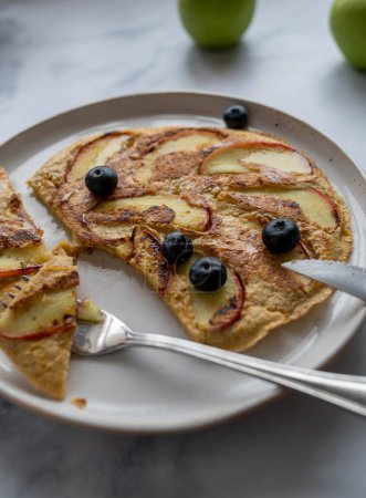 Haferflocken-Eierkuchen mit geschnittenen Äpfeln und Beeren auf einem Teller für ein gesundes Frühstück. Mahlzeit für gesunde Ernährung, Ernährung und Fitness.