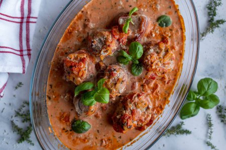 Photo for Delicious italian oven dish with pork tenderloin or pork fillet wrapped with parma ham in a delicious tomato cream sauce. Closeup - Royalty Free Image