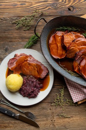 Deutscher Schweinebraten mit köstlicher brauner Soße. Traditionelle und rustikale Küche. Serviert fertig zum Essen in einer Bratpfanne auf Holztischhintergrund.