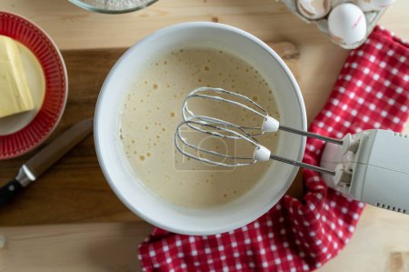 ?ufs mousseux battus avec du sucre dans un bol pour faire de la pâte ou de la pâte