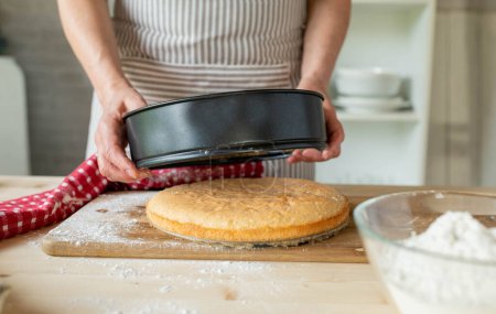 Removing cake base from a baking pan or cake pan by womans hands in the kitchen.
