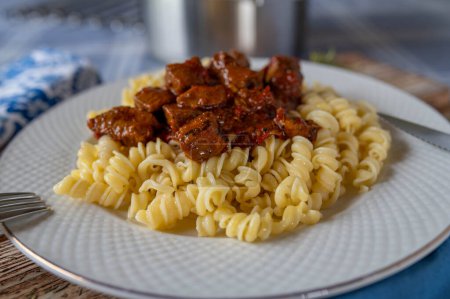 Plate with delicious goulash, hungarian style with pasta isolated on a table. Closeup