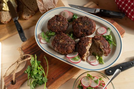Rustic food. Dinner with fresh fried pork meatballs, sourdough bread, butter and radish salad on wooden table