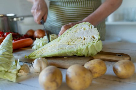 Cutting pointed cabbage by womans hand in the kitchen