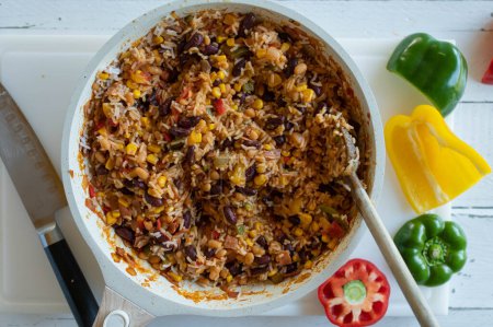 Photo for Healthy rice dish with ham, kidney beans, corn, peppers, onions, tomatoes and herbs. Low fat and high protein dinner or luch for fitness or healthy eating  in a frying pan - Royalty Free Image