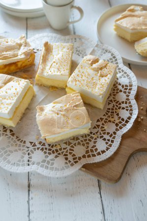 Gâteau au fromage avec garniture meringue et gouttes dorées. Gâteau déchiré traditionnel servi tranché sur un plateau de gâteau sur fond de table blanche
