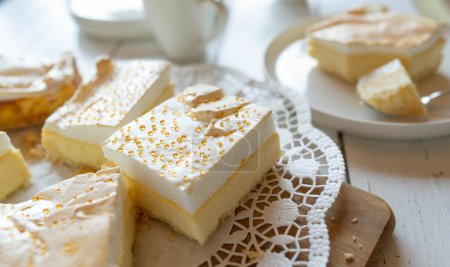 Käsekuchen mit Baiser-Topping und goldenen Tropfen. Traditionelle Tränenkuchen serviert in Scheiben geschnitten auf einem Kuchenteller auf weißem Tischhintergrund
