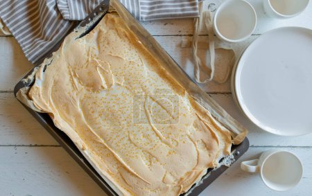 Pastel de queso polaco con cobertura de merengue y gotas de oro. Torta de desgarro tradicional. Servido entero sobre fondo de mesa de madera blanca desde arriba. Hornear o fondo de la receta