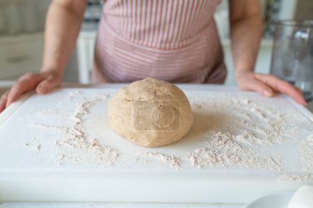 Woman with a fresh kneaded whole wheat pizza dough in the kitchen. Front view